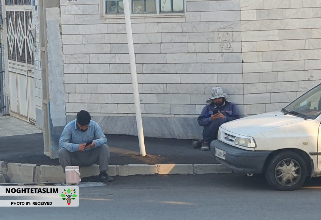 ۲ کارگر افغانی کنار یکدیگر بدون صحبت و مشغول شبکه&zwnj;های اجتماعی